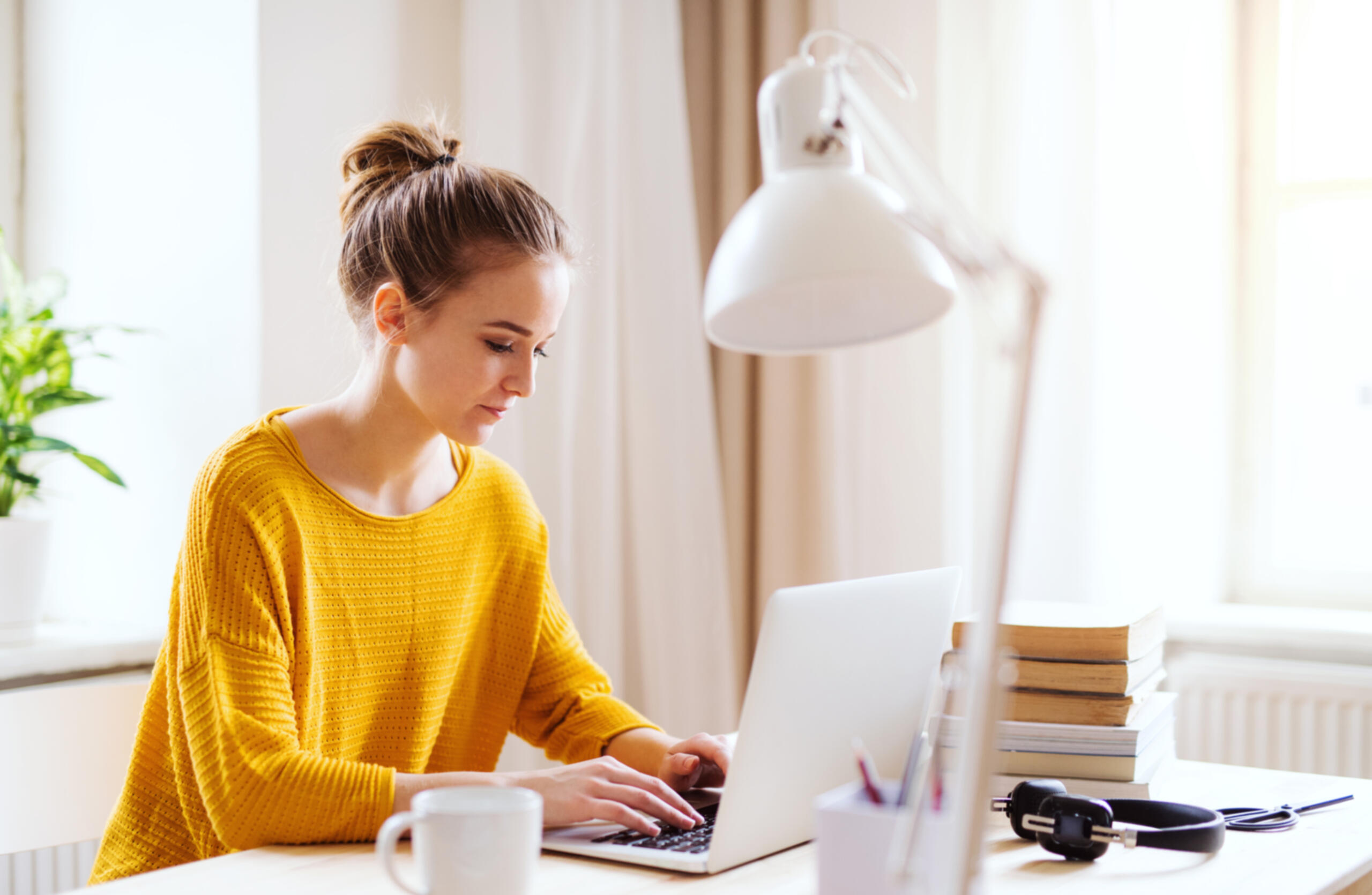 A young female student sitting at the table, using laptop when studying.